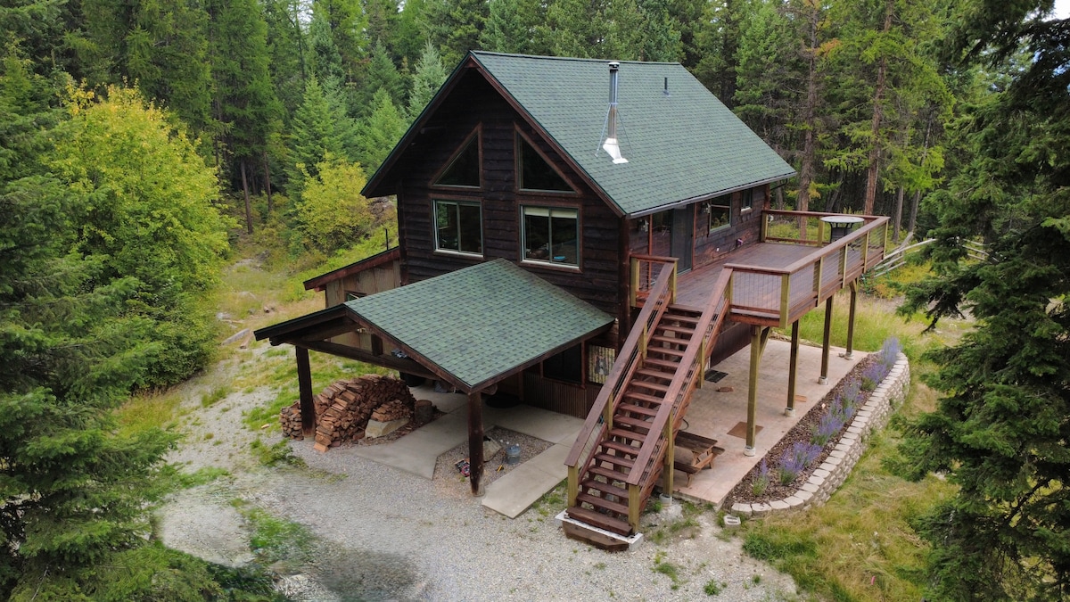 Cabin exterior with wraparound deck nestled in the pines