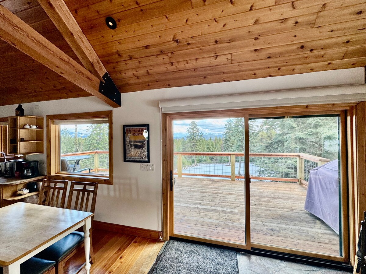 View from the dining area through sliding doors to the deck and mountains